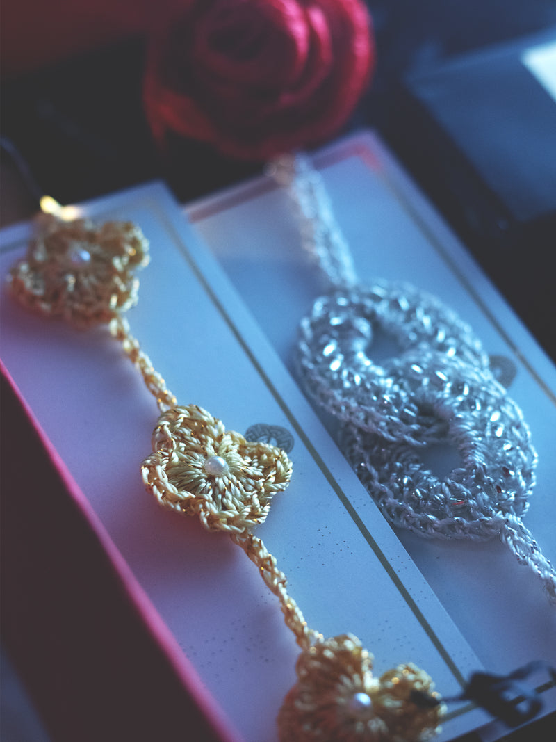 Gold and silver jewelry on a reflective surface with a blurred background